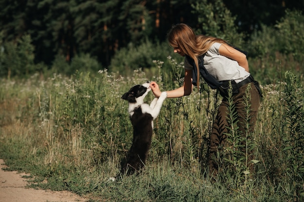 Photo girl playing with black and white border collie dog puppy on the forest path