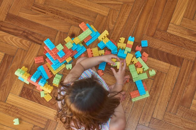 Девушка играет с кубиками на деревянном полу в своей комнате