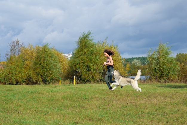 Girl playing with husky dog in city park. Jogging with dog.