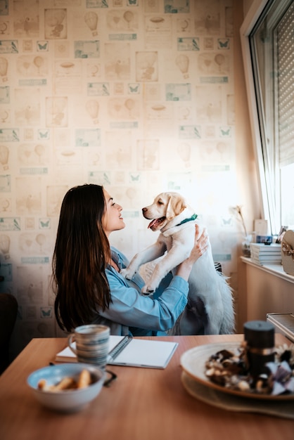 Foto ragazza che gioca con il cucciolo di labrador al chiuso.