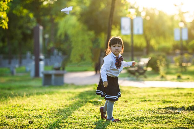 A girl playing with a paper airplane in the park