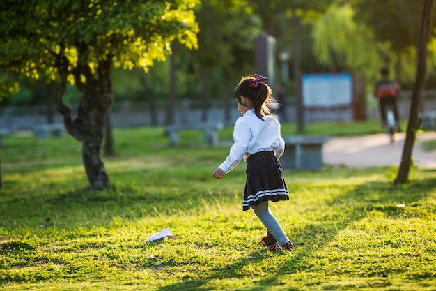 Una ragazza che gioca con un aeroplanino di carta nel parco