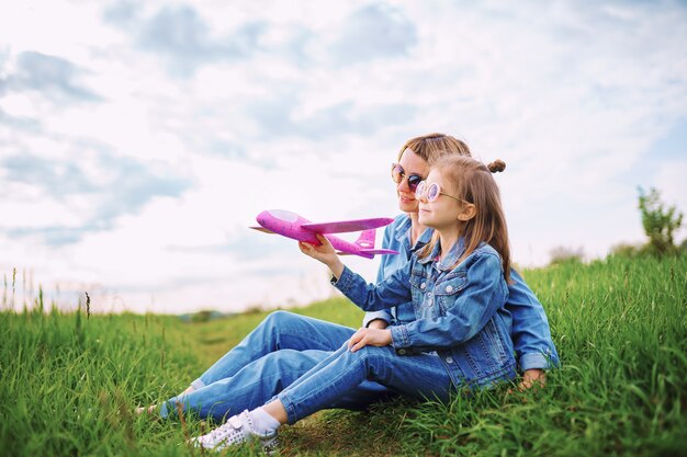 Photo girl playing with plane near mother