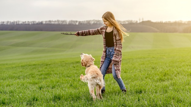 Girl playing with retriever in nature