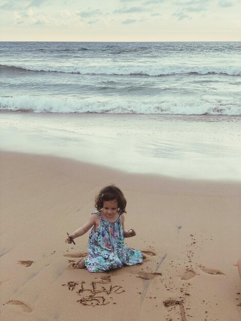 Photo girl playing with sand at beach during sunset