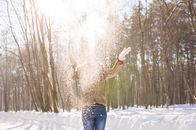 公園で雪で遊ぶ女の子。雪の中で楽しんで幸せな若い女性