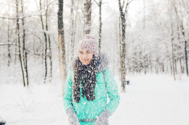 Girl playing with snow in park. Happy young woman having fun in the snow