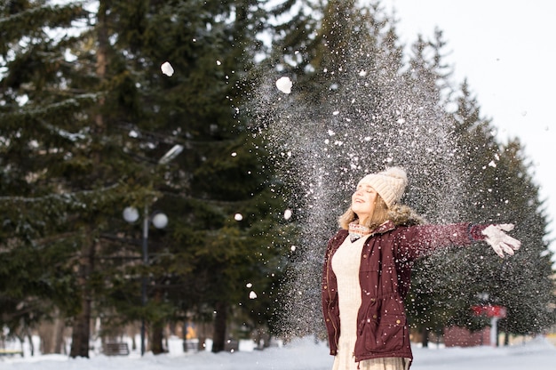 公園で雪で遊ぶ女の子。雪の冬の服を着て幸せな女の子の肖像画