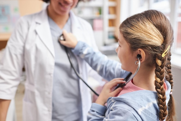 Girl playing with stethoscope in pediatric clinic