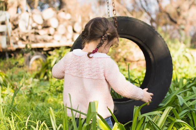 Девочка играет с шиной в зеленой траве