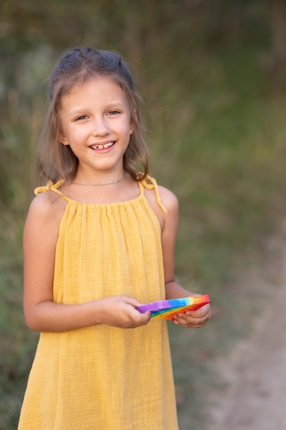 Girl playing with a toy pop it, in nature