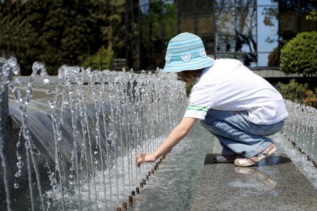 都市公園で噴水の水で遊ぶ女の子