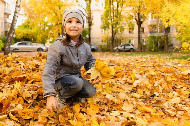 The Girl plays in autumn foliage