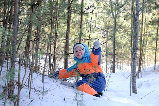 女の子は雪の上で冬の森で遊ぶ