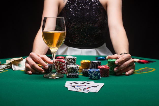 Girl plays poker in a casino with chips, dollars, and wine