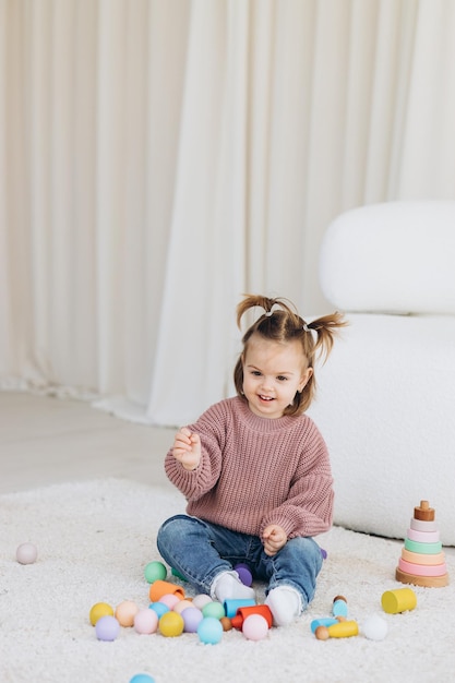 Girl plays toys in living room Montessori wooden toy folded pyramid Circle triangle rectangle wooden elements of children39s toys colored toy blue yellow red green