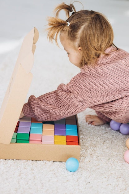 Girl plays toys in living room Montessori wooden toy folded pyramid Circle triangle rectangle wooden elements of children39s toys colored toy blue yellow red green