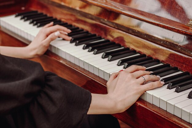 The girl plays the vintage piano at a concert close up Hands on piano keys