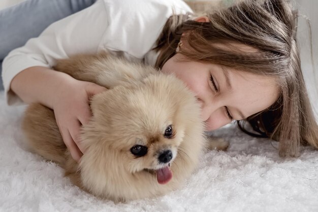 Girl plays with dog pomeranian spitz in living room