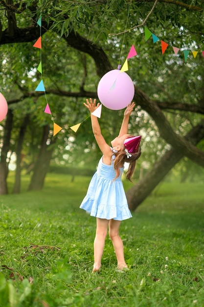 Girl plays with festive decor in garden on birthday