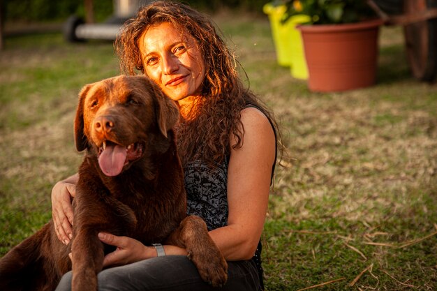 Girl plays with her labrador dog in countryside in summer\
time