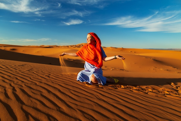 소녀는 사하라 사막에서 모래와 함께 재생됩니다. Erg Chebbi, Merzouga, 모로코.