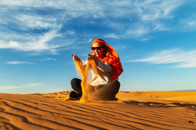 소녀는 사하라 사막에서 모래와 함께 재생됩니다. Erg Chebbi, Merzouga, 모로코.