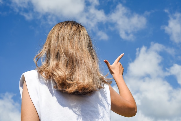 女の子は空に対して指を指します。背面図。遠くのシルエット方向方法選択景観リゾート遠足コンセプト。