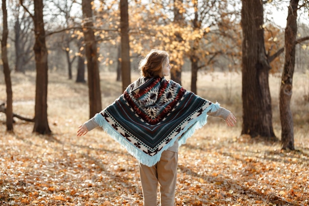 A girl in a poncho a walk in the autumn forest