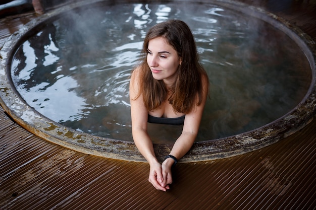 Ragazza in piscina con acqua calda in terrazza, trattamenti spa per il corpo. relax all'aria aperta, benessere. cottage con vasca idromassaggio. jacuzzi all'aperto. jacuzzi con una ragazza. bella figura di donna in costume da bagno