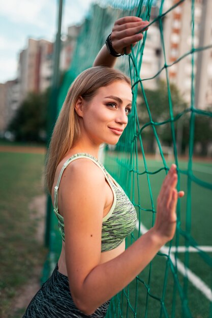 サッカーゴールのネットでポーズをとる少女