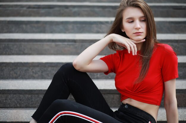 A girl posing on the steps of a building in sunny weatherxA