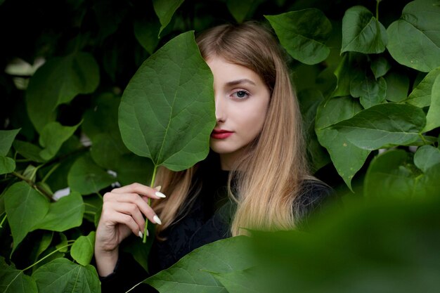 Girl posing on the wall with green leaves