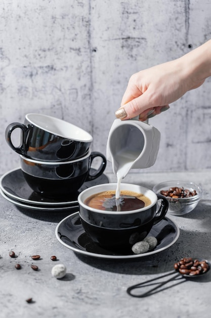 Girl pouring milk from jug in coffee cup