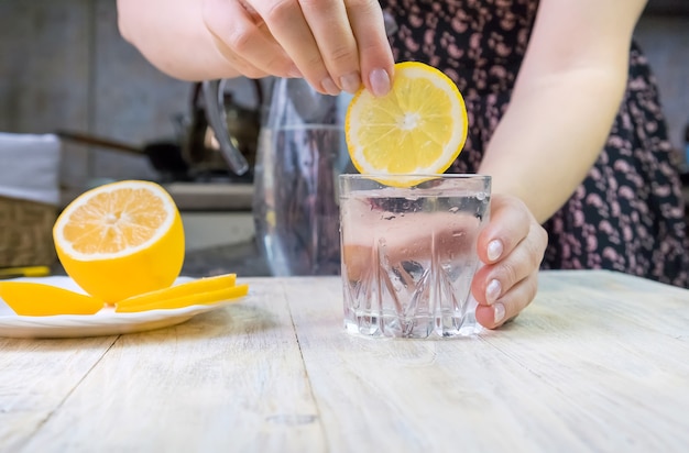 The girl pours water with lemon. Selective focus. Drink.