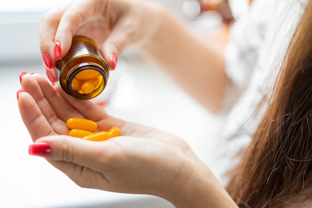 The girl pours the yellow capsules medication into her\
hands