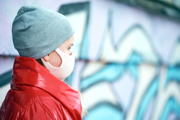 Photo girl in a powder mask and in a red jacket looks away