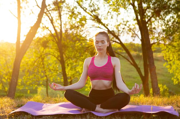 The girl practices yoga on the background of trees