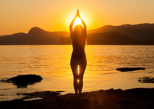 Girl practices yoga in the mountains on the ocean.