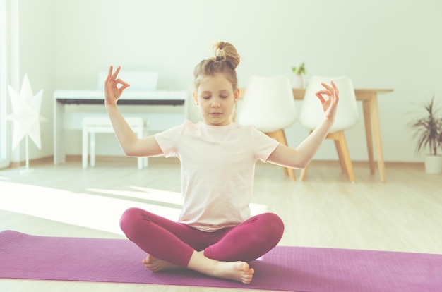 Photo girl practicing yoga on mat at home