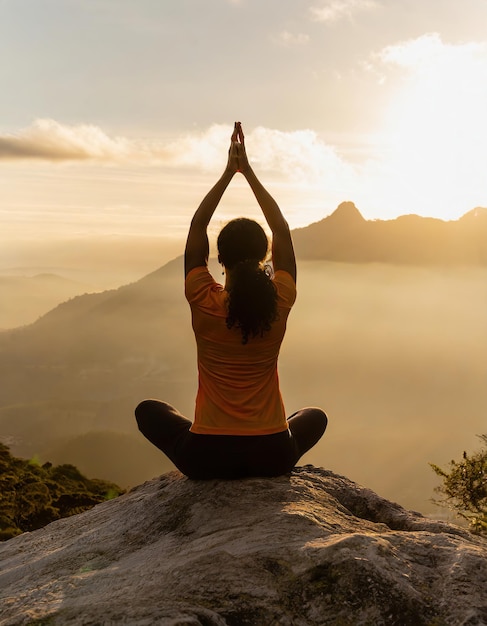 girl practicing yoga on a rock in mountain