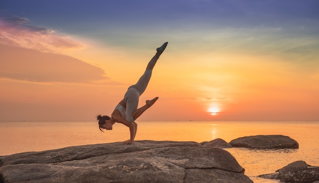 Photo girl practicing yoga on a rock