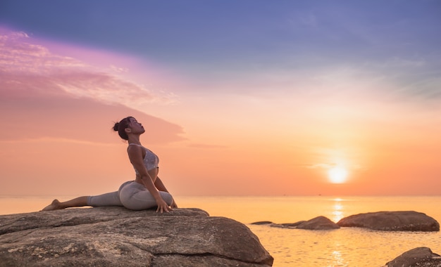 Photo girl practicing yoga on a rock