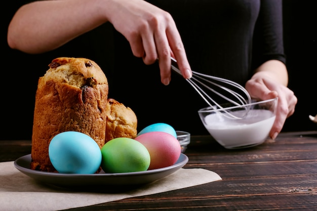 The girl prepares Easter baking, smears the cake with icing and sprinkles with colored powder