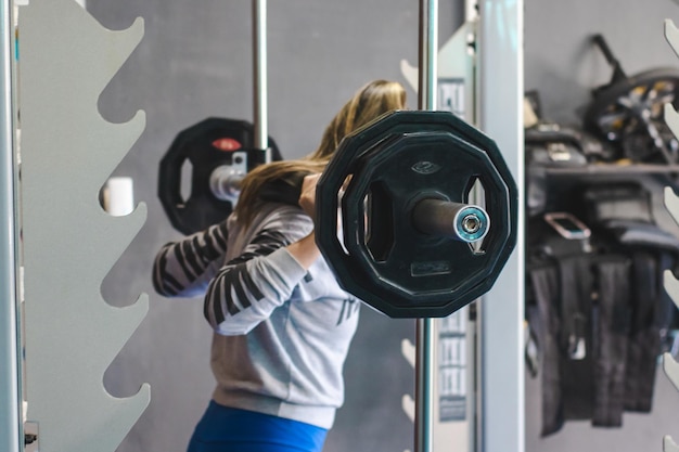 Girl preparing to do barbell squats in a gym