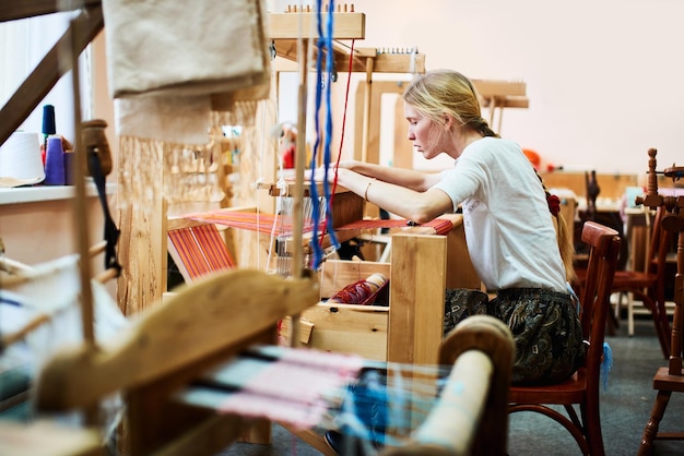 Девушка в процессе производства текстиля ручной работы на ткацком станке.