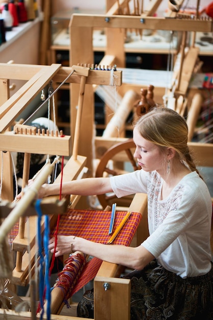 The girl in the production process of textiles are handmade on a loom