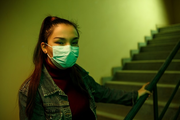 階段の吹き抜けで使い捨ての保護医療マスクの女の子