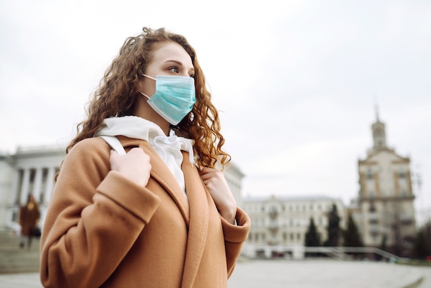 Ragazza nella mascherina medica sterile protettiva sul suo fronte sulla strada