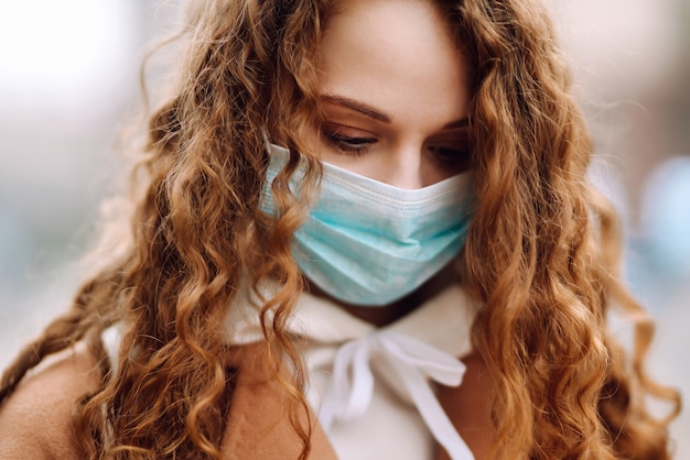 Ragazza nella mascherina medica sterile protettiva sul suo fronte sulla strada